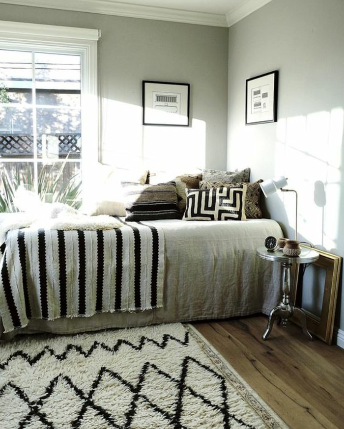 chambre design en beige clair avec des murs en couleur pistache tapis en losanges noirs et blancs