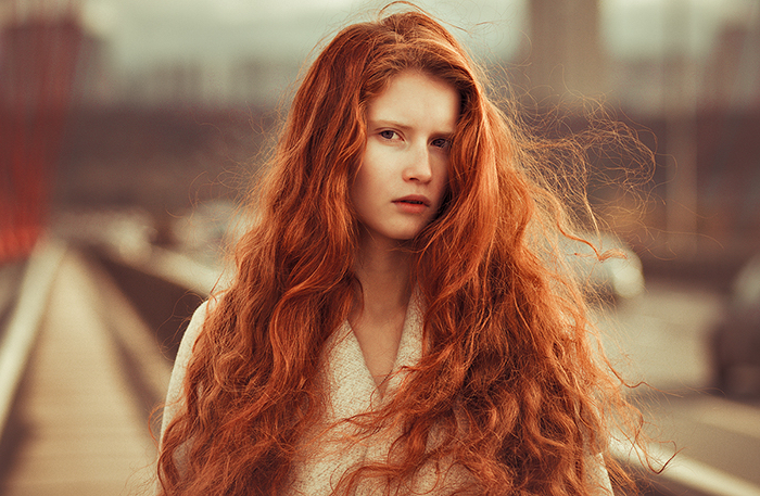 couleur cheveux cuivré, femme devant la gare, cheveux longs en orange, boucles légères, yeux marron