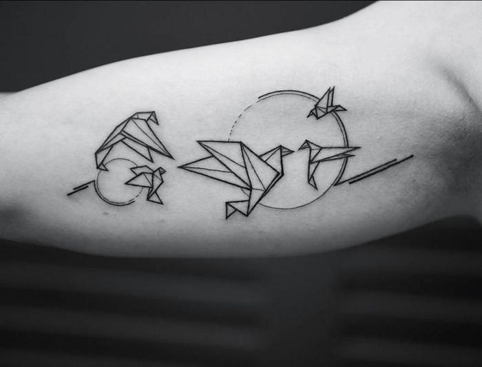 tatouage géométrique à l'intérieur du bras composé de grues en origami et deux soleils