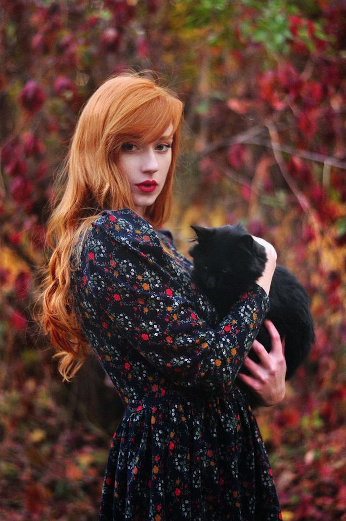 roux cuivré, femme dans la forêt, animal de compagnie chat noir, coiffure orange avec boucles, rouge à lèvres nuance rouge