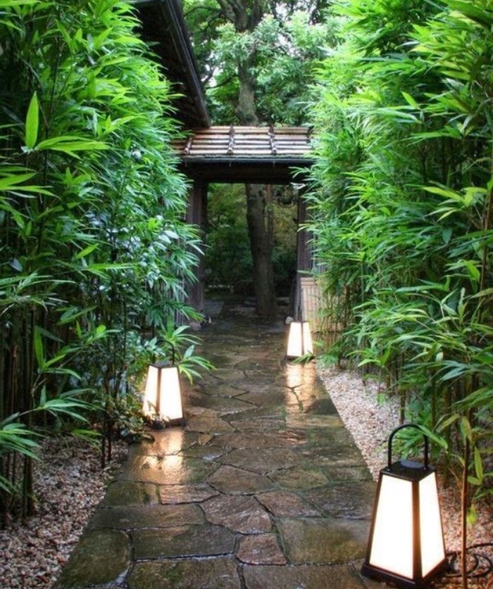 une chemin entrée cour maison, sentier de pierres avec bambou des deux côtés et lanternes comme éclairage exterieur