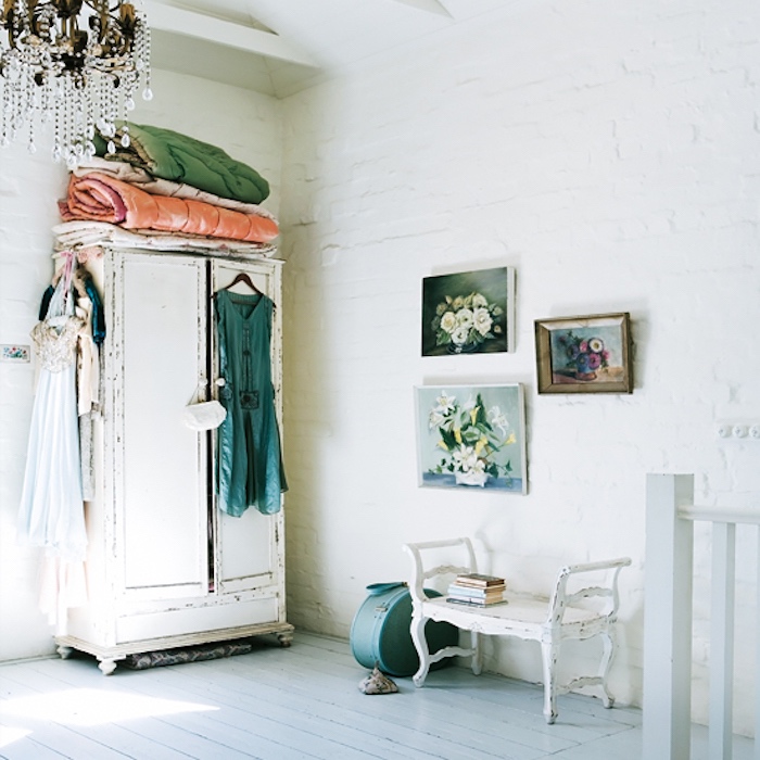 chambre shabby chic femme, parquet blanc, mur-de-briques blanchies, armoire blanche patinée, robes multicolores, lustre élégant