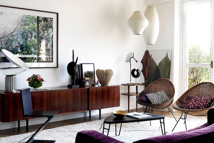 motif tribal, salon aux murs blancs, chaise en rotin avec coussins à motifs ethniques, canapé en velours violet, peinture nature