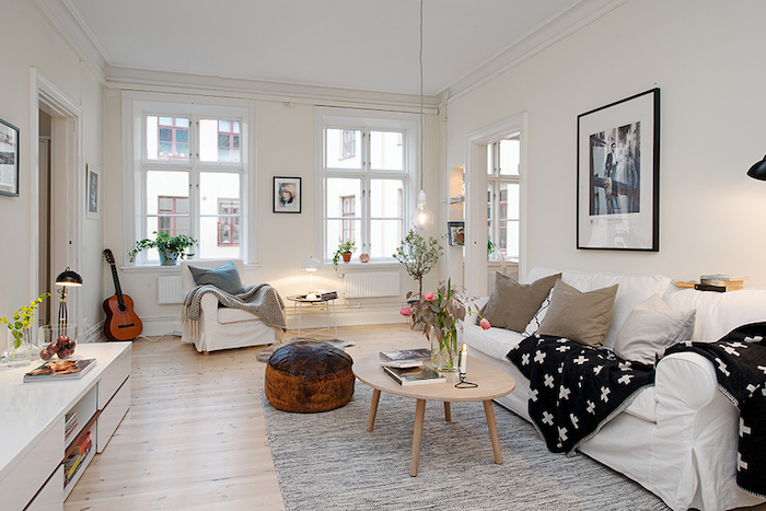 deco scandinave salon, canapé blanc avec coussins marron, parquet en bois clair, plantes vertes, pouf en cuir marron