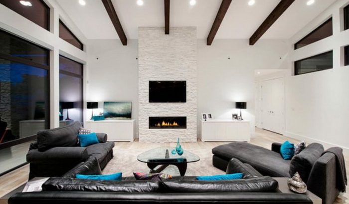 deco salon contemporain, sofas en cur noir et coussins bleus, poutres apparentes sur un plafond blanc