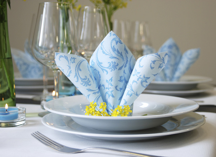 technique origami avec serviette en papier, arrangement de table en blanc et bleu, serviette en papier bleue