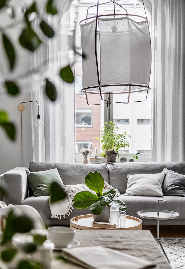 deco salon style scandinave, tapis à motifs géométriques en beige, canapé en tissu gris avec coussins décoratifs