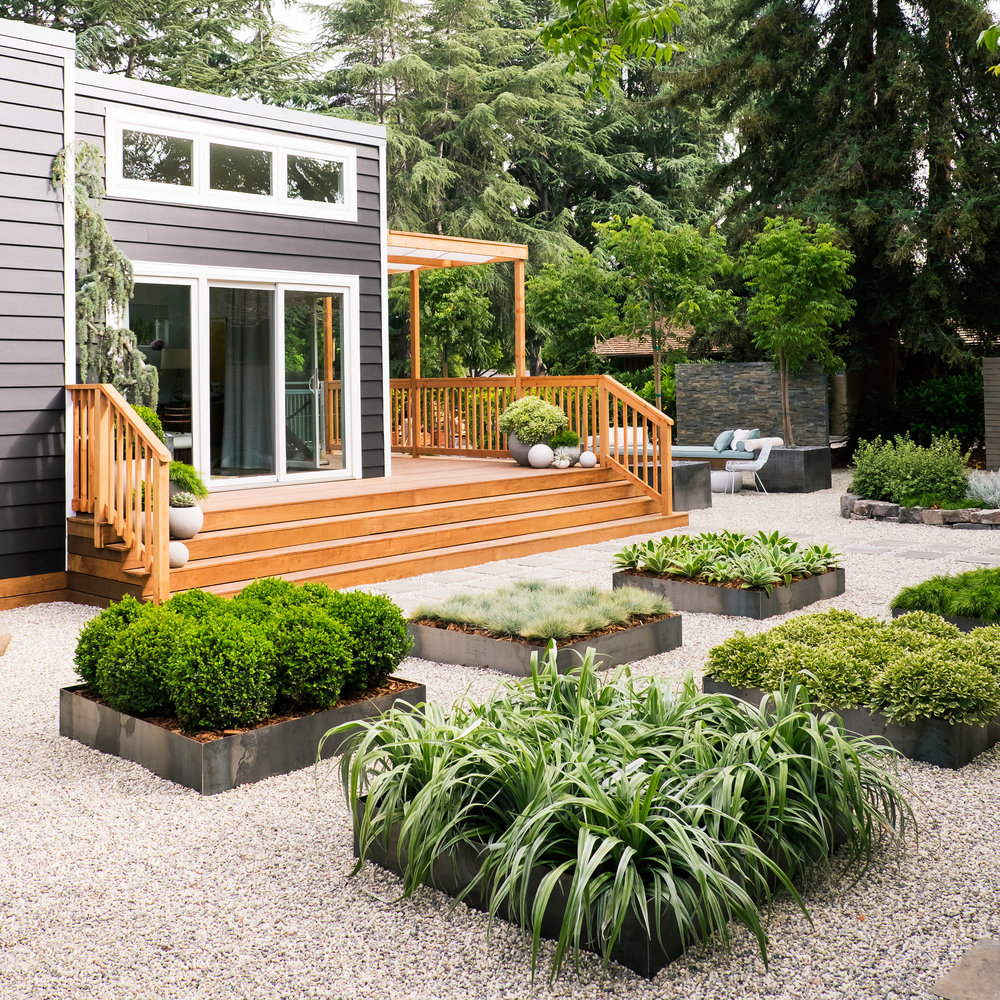 déco de jardin zen, gravier sur le sol, petits carrés végétalisés, maison ultra moderne dans un cadre naturel espace détente au fond