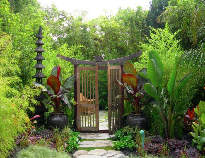 decoration zen de chemin de pierres, arbustes et bambou avec des vases des deux cotés d une porche cochère japonaise