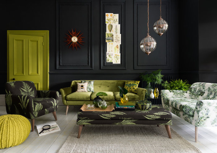 tissu tropical, comment décorer le salon, murs peints en noir, horloge soleil rouge, canapé en velours vert, tapis beige, plantes vertes