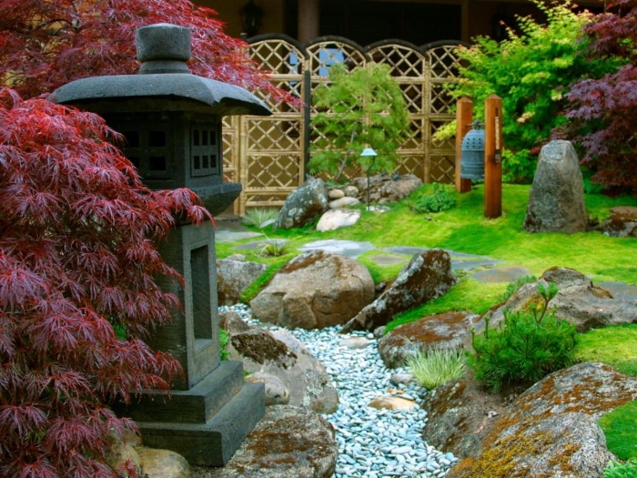 idée comment aménager un jardin zen minimaliste, gazon, rivière en pierres, entouré de grosses pierres, lanterne, lampe en pierre, arbres et plantes japonaises