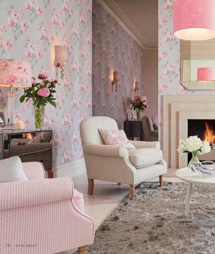 tapis gris, papier peint bleu à fleurs rose, fauteuil gris et fauteuil rose, table basse blanche, cheminée romantique, bouquets de fleurs