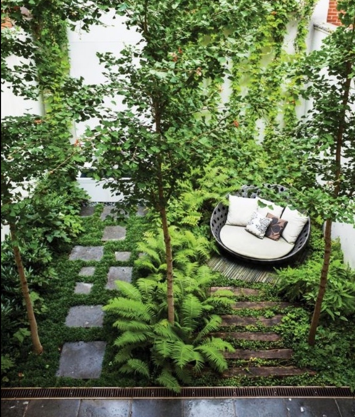 exemple amenagement jardin, canapé rond design sur un lit en bambou, chemin de dalles de pierre, arbustes, arbres 