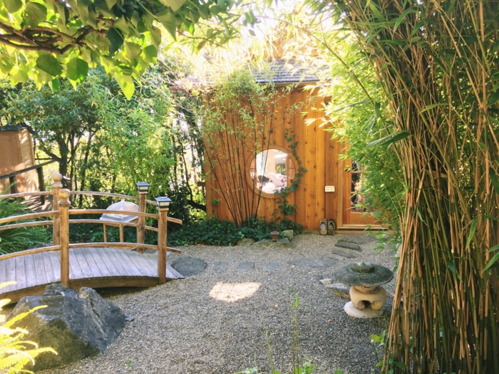 amenagement jardin zen, sol recouvert de gravie et pierres, chemin en pierre, pont en bois, chalet, cabane en bois, cloison en bambou