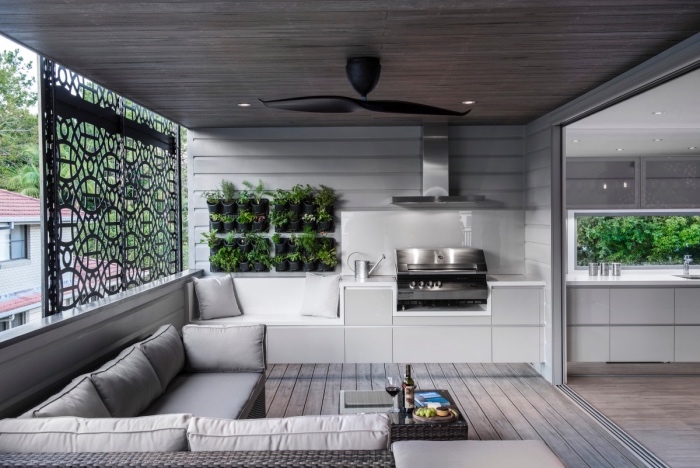 amenager petite cuisine blanche, avec aspirateur inox, parquet et canapé gris avec un mur végétale verte pour une touche zen, table basse en rotin