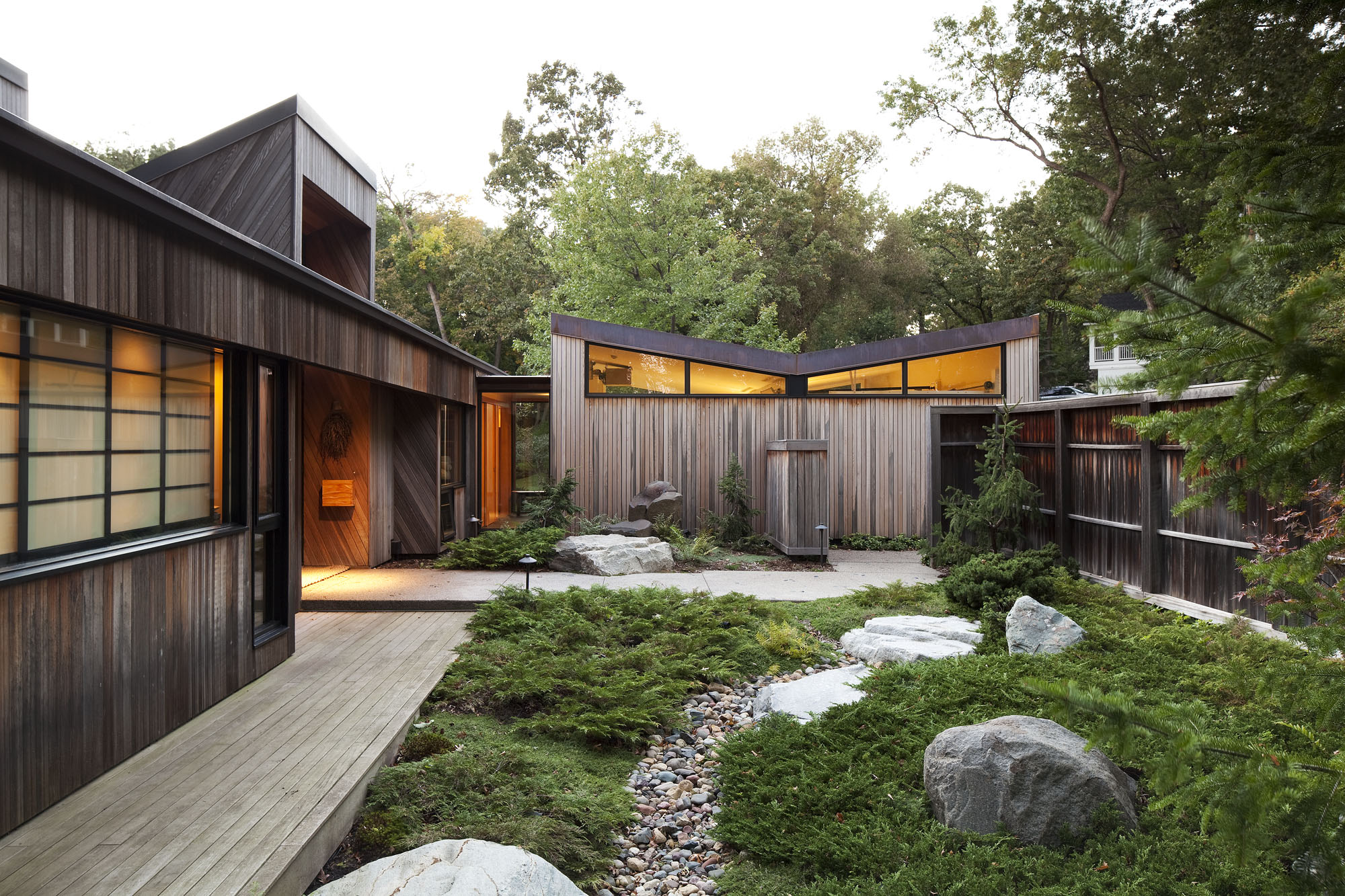 idée de maison moderne avec un jardin zen, chemin de galets, plante couvrant sol et grosses pierres, clôture en bois