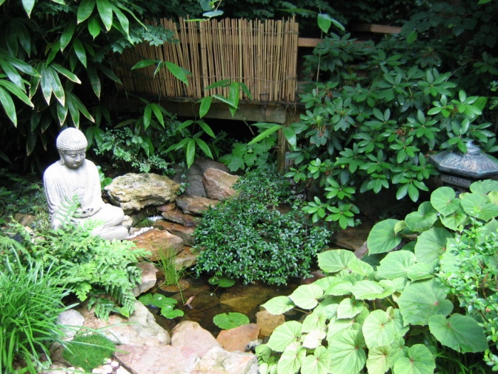 déco de jardin zen, un petit bassin d eau, fontaine, entourée de pierres, statue bouddha, vegetation verte