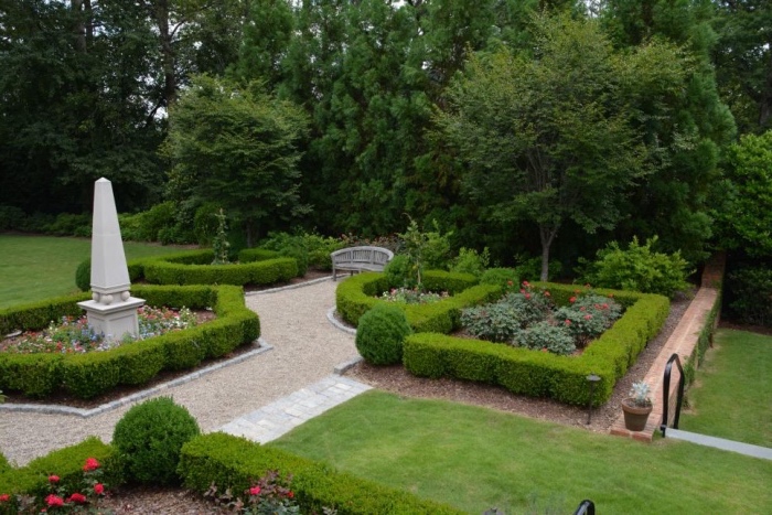 idee jardin amenagement, plusieurs espaces verts, gazon, buis rosiers et autres arbustes, fleurs dans un ajrdin à la française avec une sculpture
