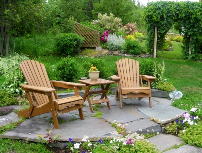jardin zen, pelouse et fleurs, un terrain en pierres, coin repos, table et chaise longue en bois, vegetation florissante