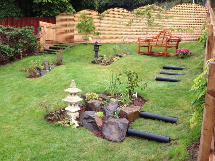 decoration zen jardin en pente, pierres, lanterne, banc en bois, cloture en bois, idée amenagement extérieur végétalise