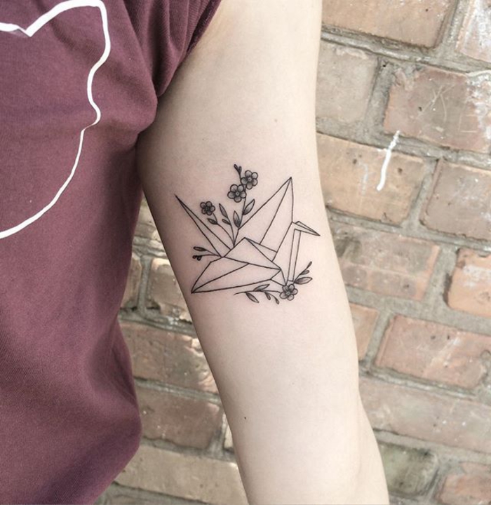 un tatouage japonais discret inspiré de l'art d'origami qui représente une grue de style géométrique associée à une branche fleurie délicate
