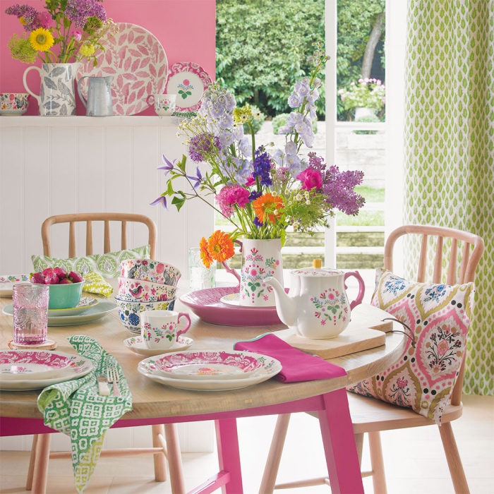 décoration shabby chic salle à manger, table palteau en bois clair et pieds rose, chaises en bois clair, mur couleur rose poudré, vaisselle shabby chic à motifs floraux, rideaux vert pistache, bouquet de fleurs