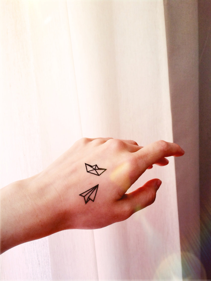 idée originale pour un tatouage minimaliste délicat et féminin sur la main, de petits bateau et avion en papier inspirés de l'art d'origami
