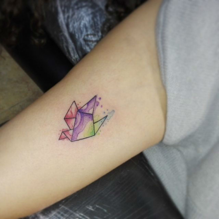 une petite grue aquarelle tatouée au bras, idée pour un tatouage minimaliste doux et féminin