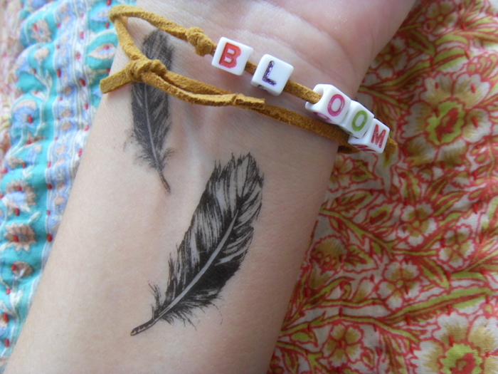 tatouage femme, bracelet avec lettres pour femme, tatouage sur le poignet à petites plumes