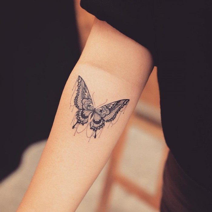  tatouage main homme, tenue pantalon et t-shirt noir, tatouage sur le bras en design papillon