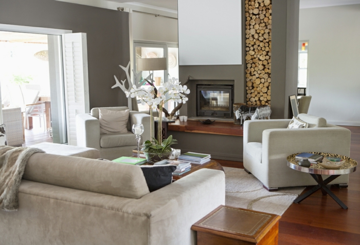 idée déco salon moderne, range-buche décoratif, sofas gris, sol en bois, grands canapés
