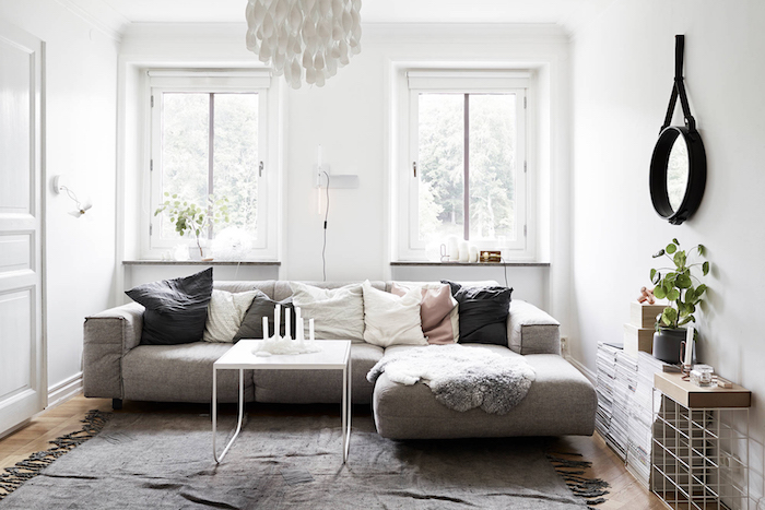 mobilier scandinave, parquet en bois clair, miroir rond en noir, murs peints en blanc, table en blanc, tapis gris avec franges