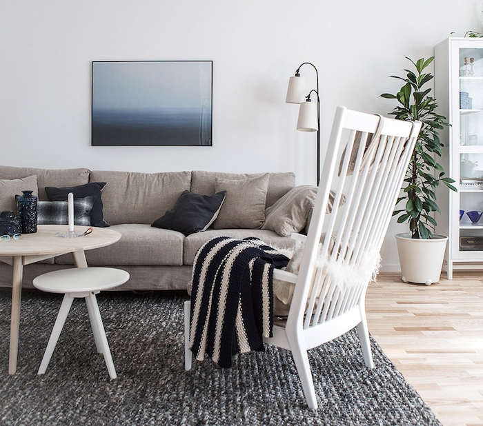 inspiration scandinave, parquet de bois, grande chaise en bois peinte en blanc, canapé en tissu beige avec coussins décoratifs
