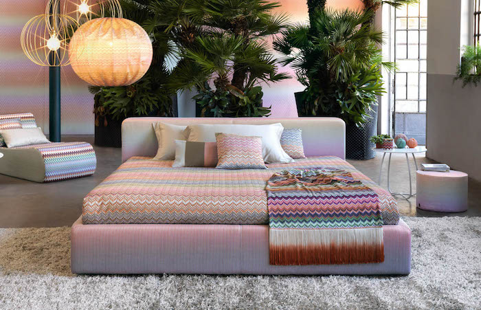 motif géométrique, lit king-size en rose pastel, couverture et linge de lit à motifs géométriques, plantes vertes tropicales