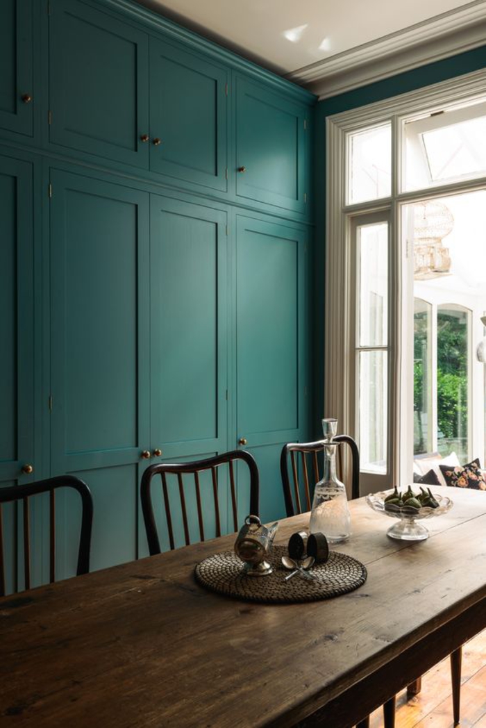 une salle à manger de style maison de campagne, ambiance naturelle et apaisante avec un mur de placards ajustés bleu paon 