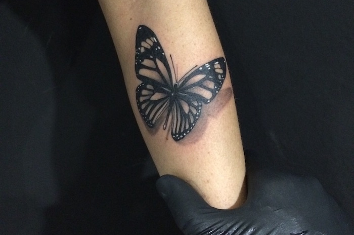 tatouage avant bras femme, tatto 3d à motif papillon noir, idée dessin en encre sur la peau pour femme