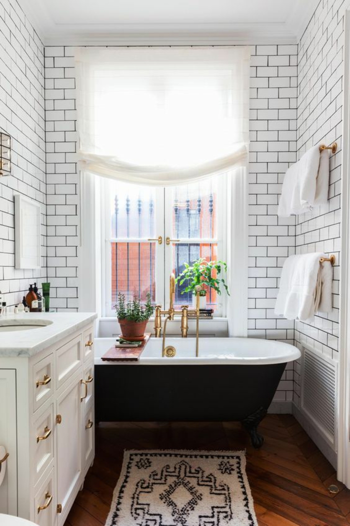 petites salle de bain aux briques blanches avec baignoire en noir et blanc et neuble blanc aux poignées imitation or