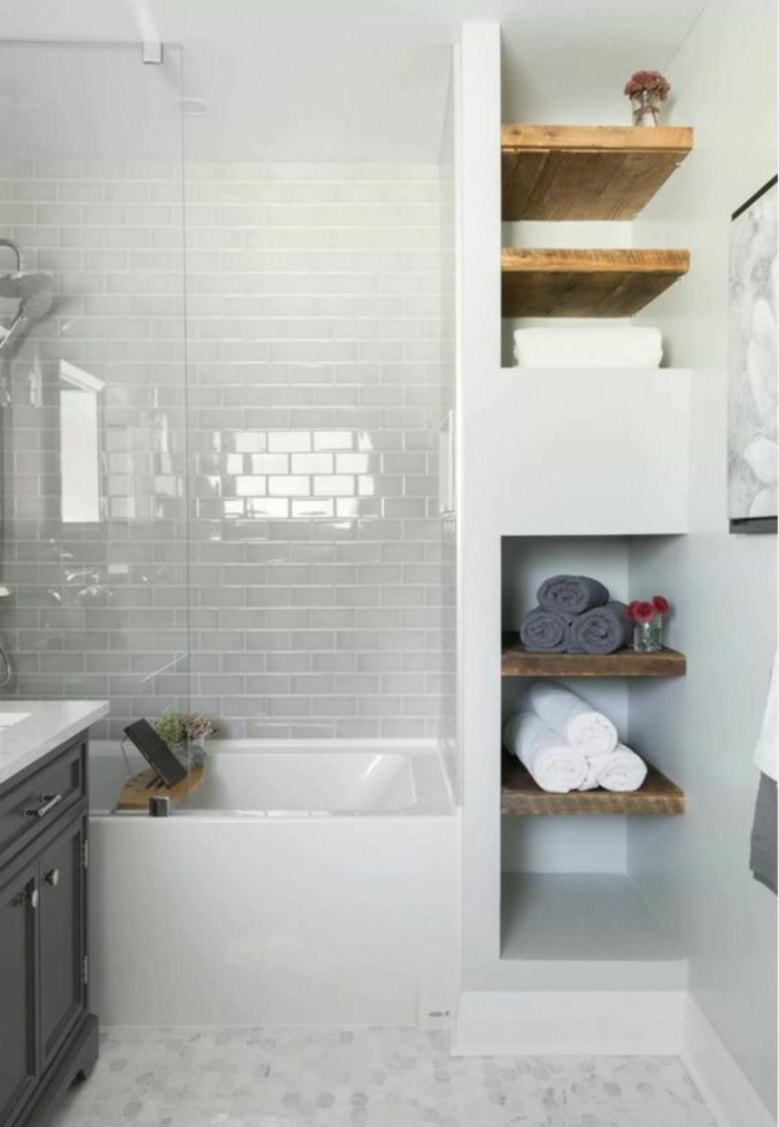 petite salle de bain aux étagères en bois marron clair avec des murs motifs briques blanches 