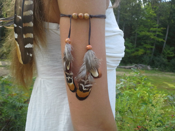 tatouage femme, bracelet avec perles en bois et plumes, coiffure avec plumes dans les cheveux, tatouage plume