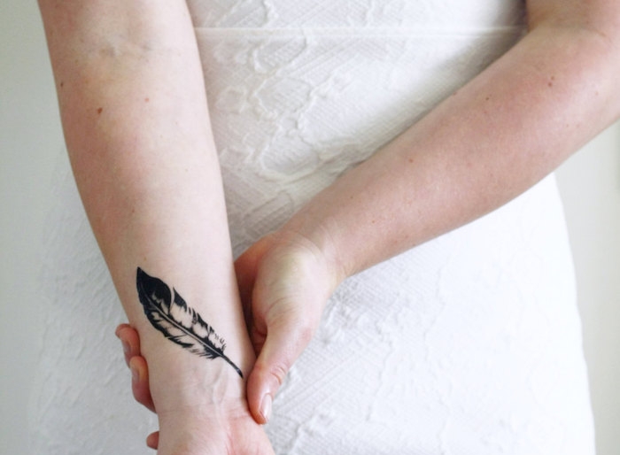 tatouage femme, dessin en encre sur la peau, tatouage sur le poignet à design plume 