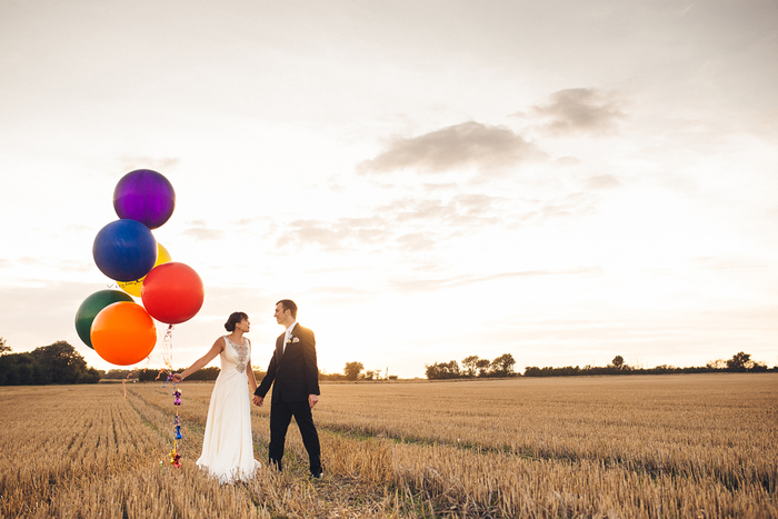 photo de couple poétique dans les champs d'automne, contraste entre les couleurs d'automne et les ballons colorés