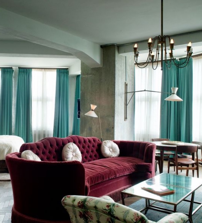 mur couleur gris anthracite, grand canapé bordeaux, table basse, fauteuil à motifs floraux, rideaux bleu canrd et lustre élégant