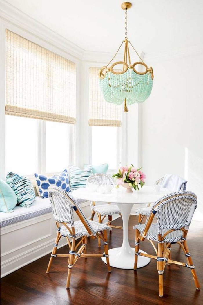 salle a manger blanche, table blanche et chaises en bois et tissu canapé blanc, coussins et lustre vert mint, bouquet de fleurs