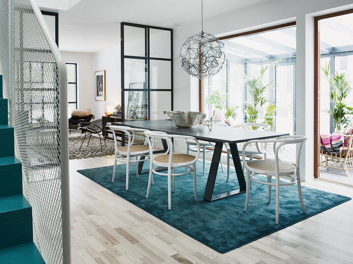 une salle à manger scandinave conviviale et lumineuse, tapis bleu paon qui délimite le coin repas