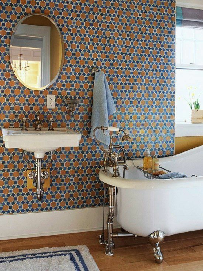 petite salle de bain aux murs en ruches bleues et oranges avec miroir rond 