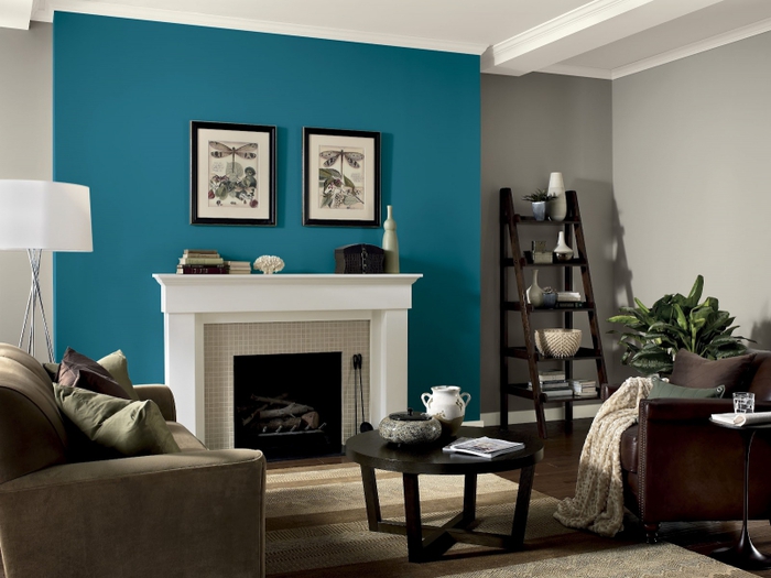salon moderne aux nuances de marron, taupe et bleu paon, pan de mur bleu qui délimité une cheminée traditionnelle