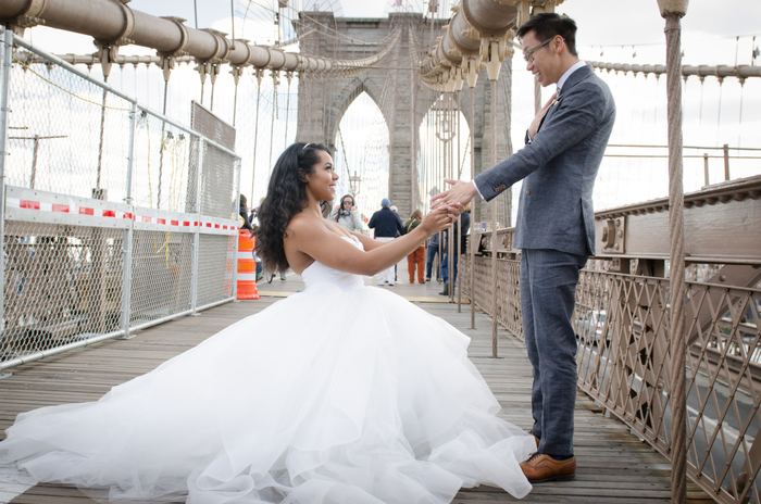 photo de couple originale sur un pont, la mariée se met à genoux