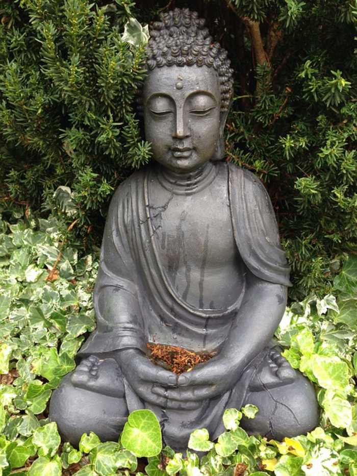 statuette de bouddha, élément essentiel de la déco de jardin zen, végétation verte exubérante, paysage oriental