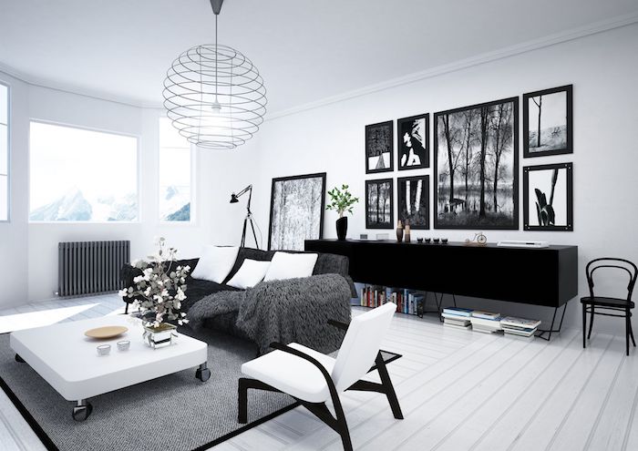 salon mur blanc, parquet en bois peint en blanc, armoire noir, cadres photo noirs, canapé noir avec coussins blancs