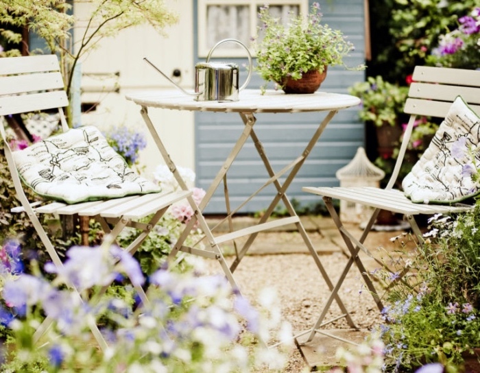 idee amenagement petit jardin, salon de kardin en table et chaise en metal, gravier dans un cadre naturel, parterres de fleurs